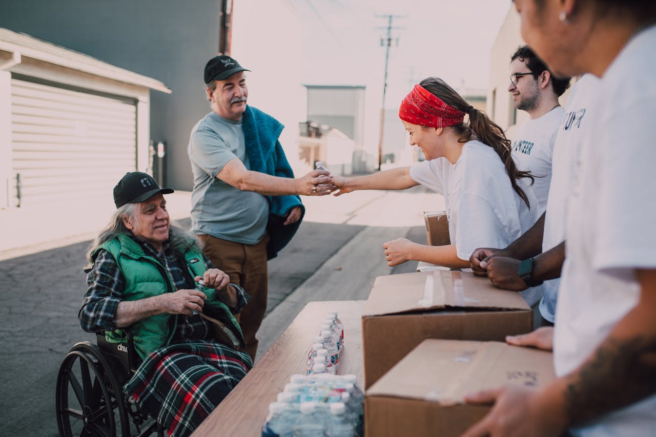 gallery-6 Volunteers distribute water and supplies to people outdoors, promoting community support and kindness.